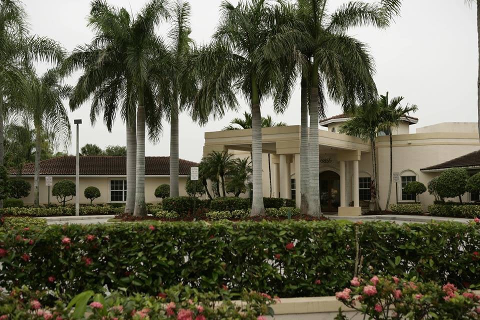 A tropical building surrounded by palm trees and a well-maintained garden.