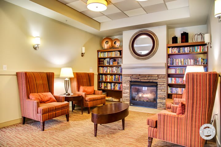 A cozy living room with a fireplace, armchairs, and bookshelves.
