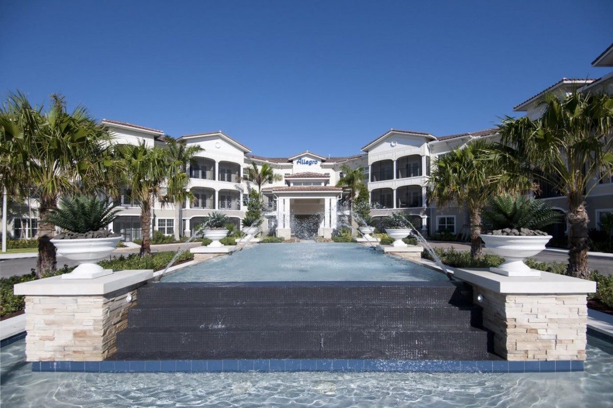 A luxurious resort building with palm trees and a grand entrance under a clear blue sky.