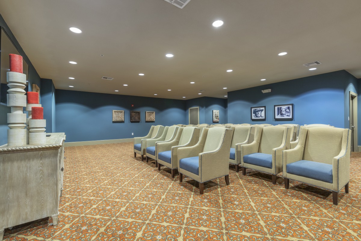 A well-lit conference room with rows of comfortable chairs and a patterned carpet.
