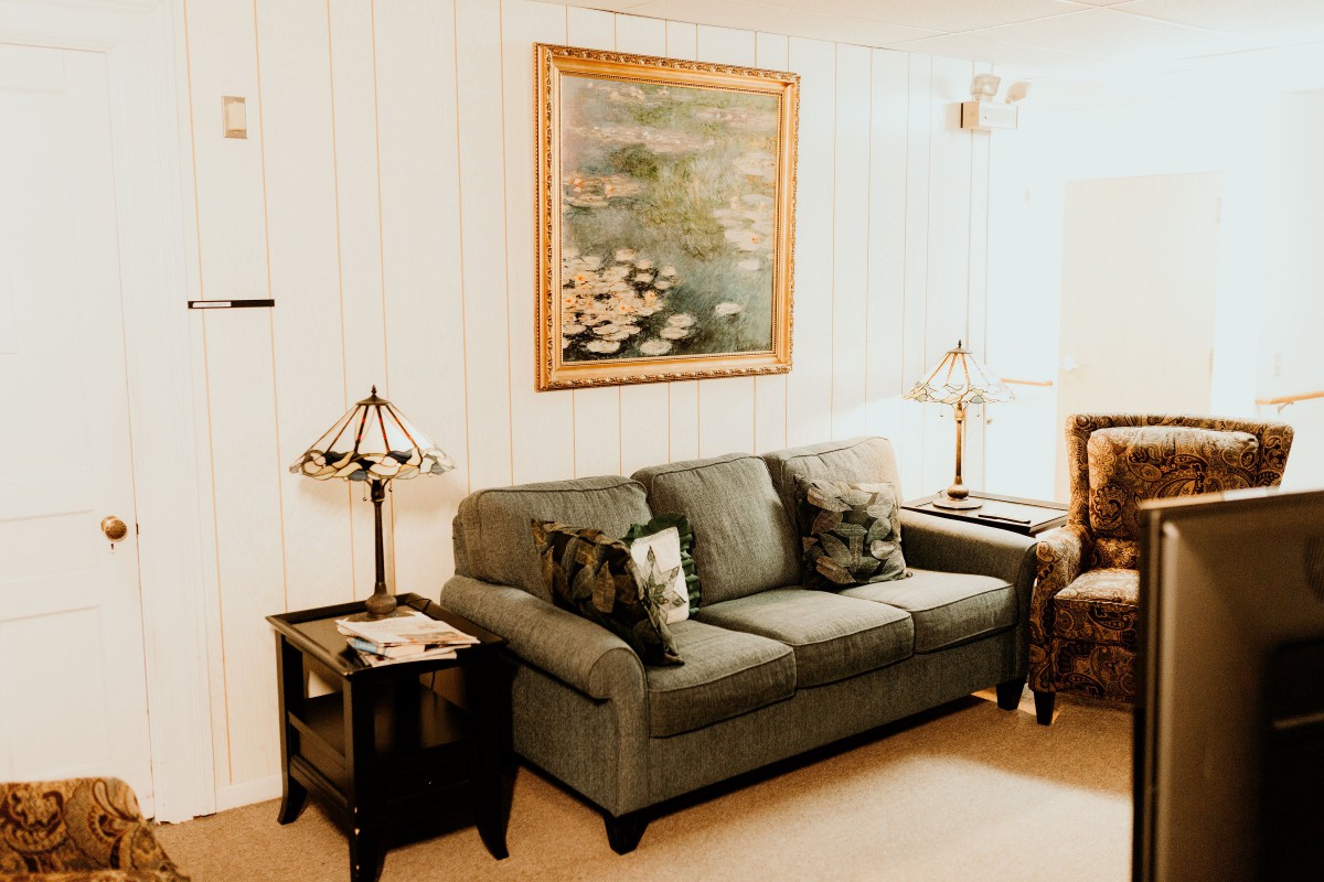 A cozy living room with a sofa, side tables, and a framed painting on the wall.