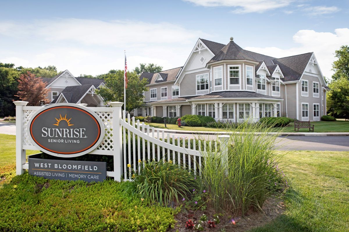 A residential-style building with a well-maintained garden and signage in the foreground.