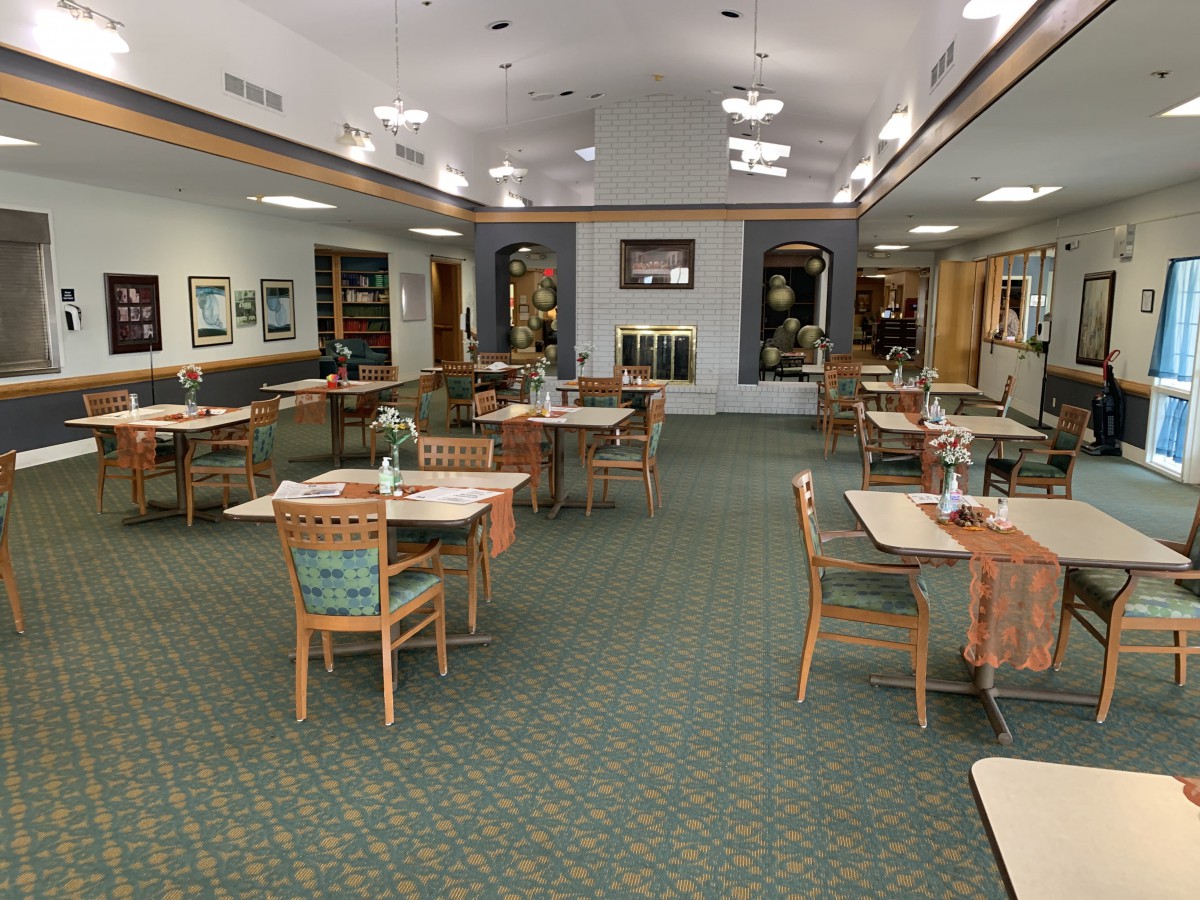 An indoor dining area with tables and chairs arranged neatly on a carpeted floor.