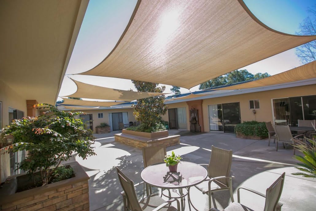 A sunny courtyard with shade sails and outdoor seating.