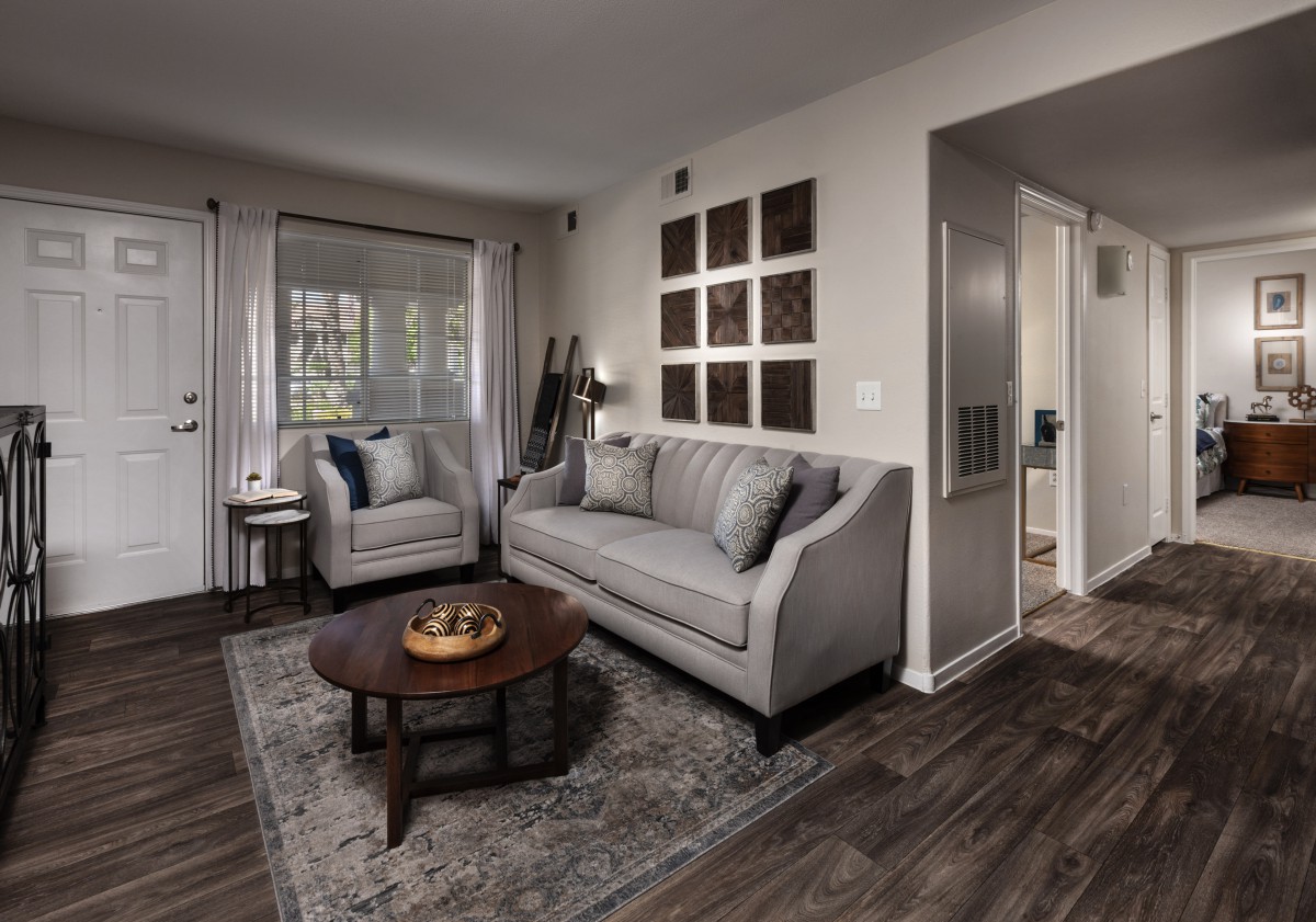 A modern living room with a cozy sofa set, armchair, and a wooden coffee table on a patterned rug.
