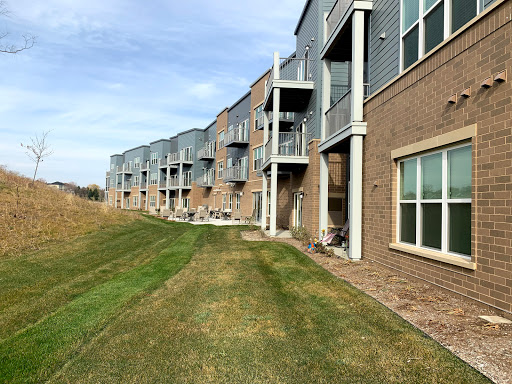 A row of modern apartments with a well-maintained lawn and clear blue sky.