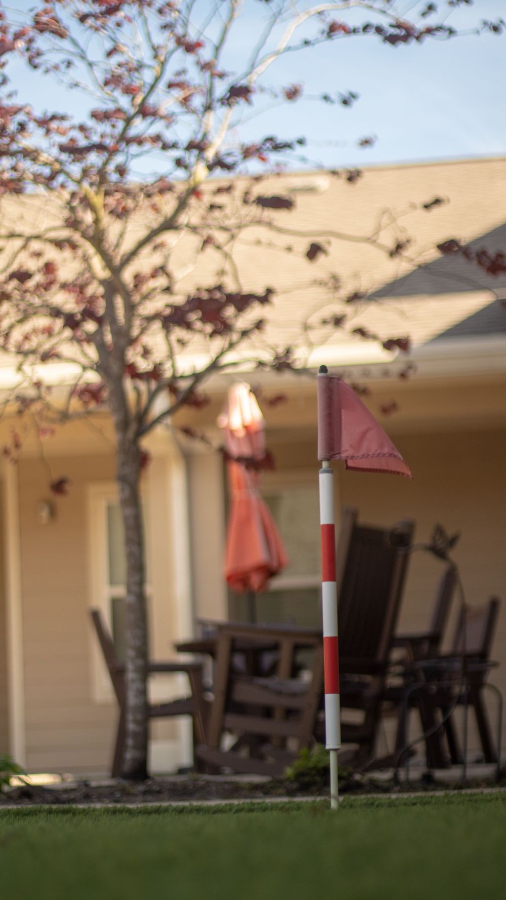 A small red flag in a backyard patio setting with outdoor furniture and a tree.
