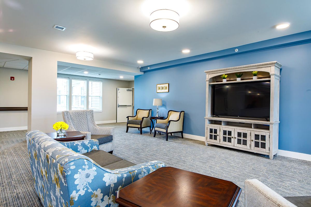 A modern living room with blue walls featuring a large television and comfortable seating.