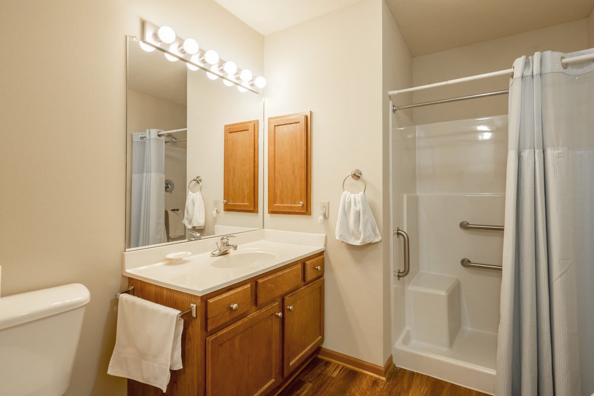 A modern bathroom with a vanity, mirror, and shower area.