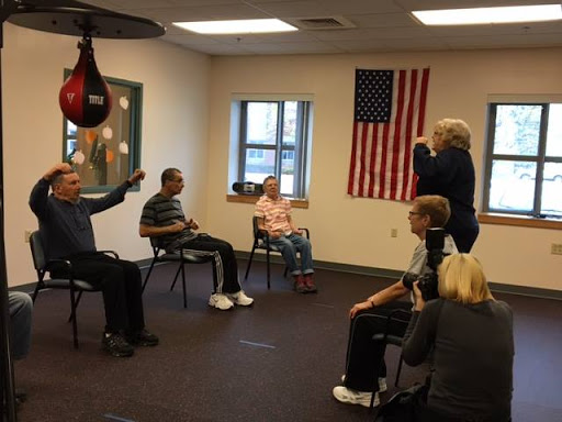 A group of seniors participating in a physical activity session, focusing on exercise and rehabilitation with a boxing bag in the background.