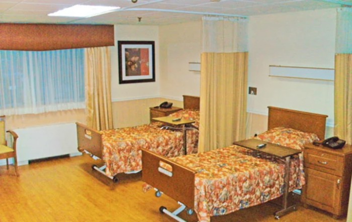 A hospital room with two beds separated by curtains.