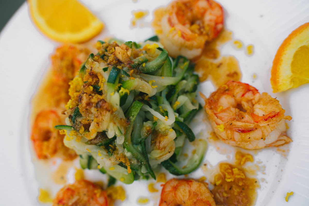 A gourmet dish featuring zucchini noodles paired with grilled shrimp.