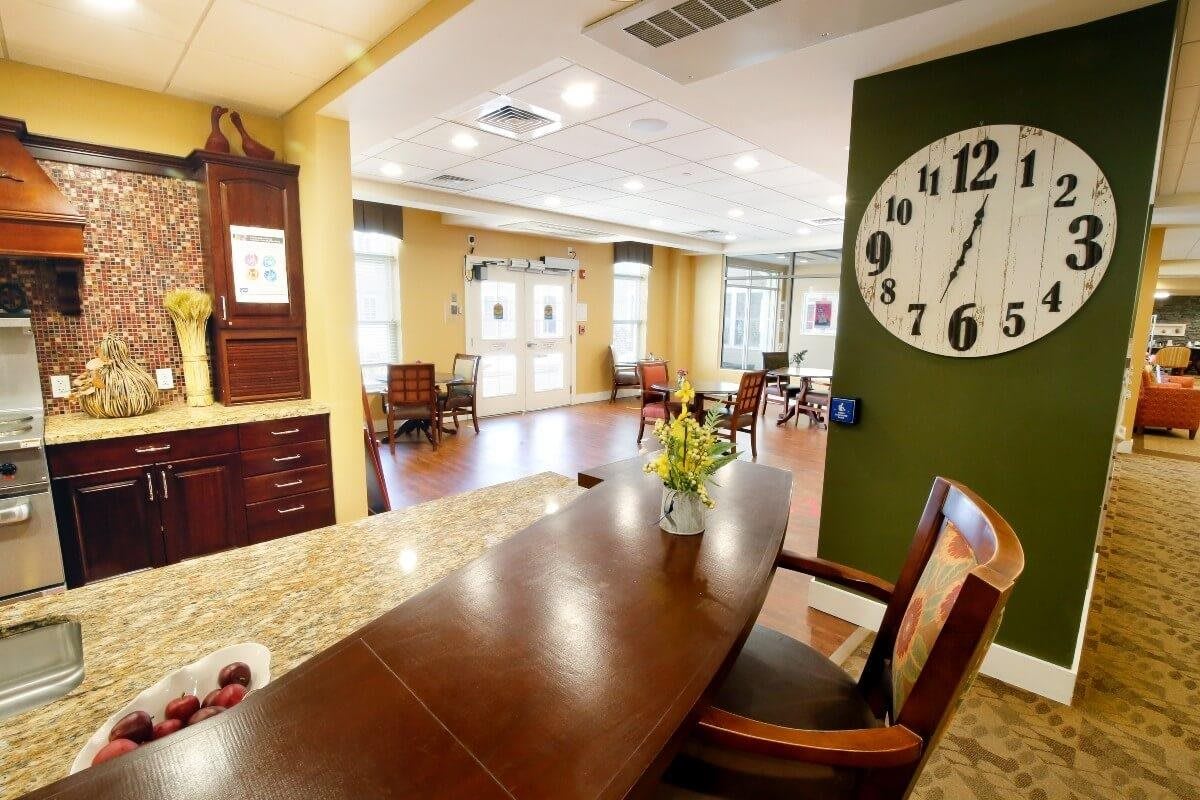 A well-lit interior space featuring a large clock, wooden chairs, and tables.