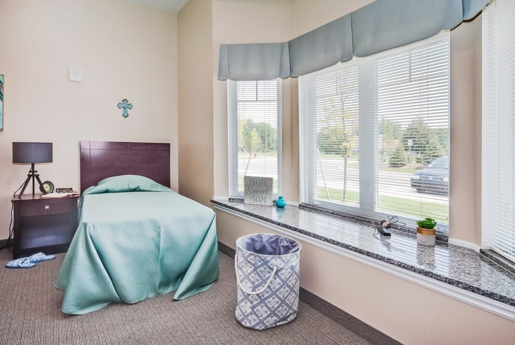 A minimalist bedroom with a single bed, large windows, and a decorative basket.