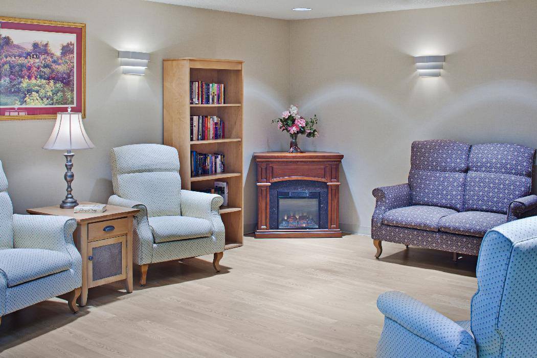 A cozy living room with comfortable seating, a bookshelf, and an electric fireplace.