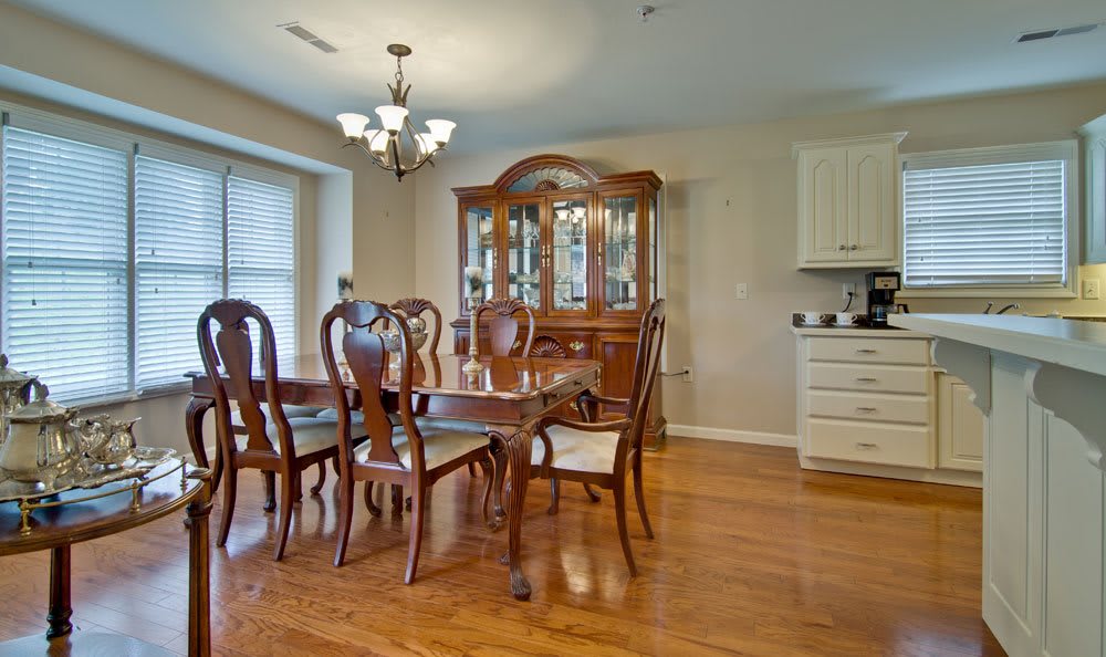 A classic dining room with a wooden table, chairs, and a cabinet on a hardwood floor.