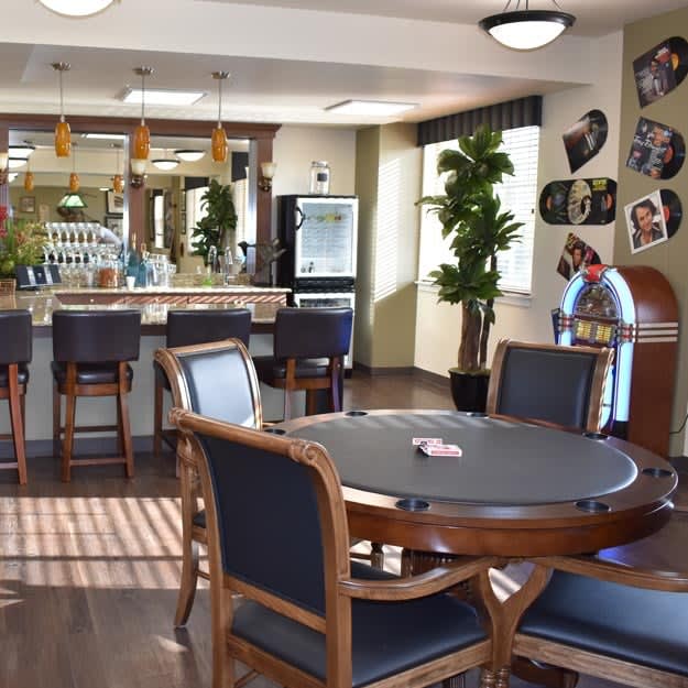 A cozy game room featuring a poker table and bar area with classic decor.
