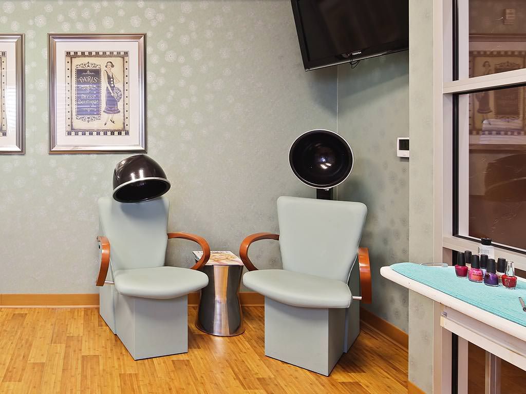 A cozy salon waiting area with two hair dryer chairs and wall decor.