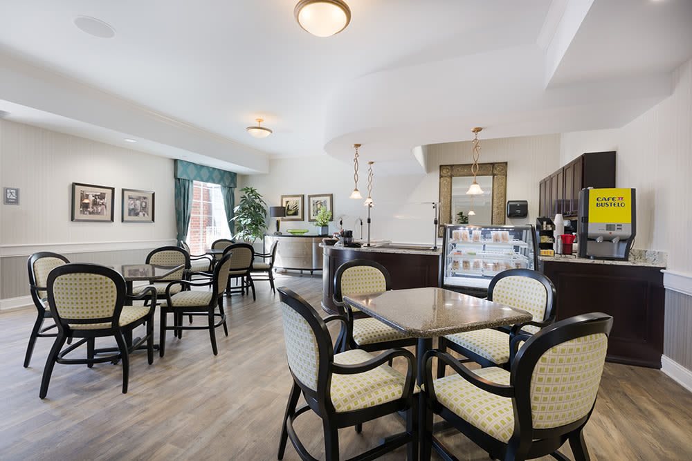 A well-lit dining area with several tables and chairs arranged neatly, featuring elegant decor and ambient lighting.