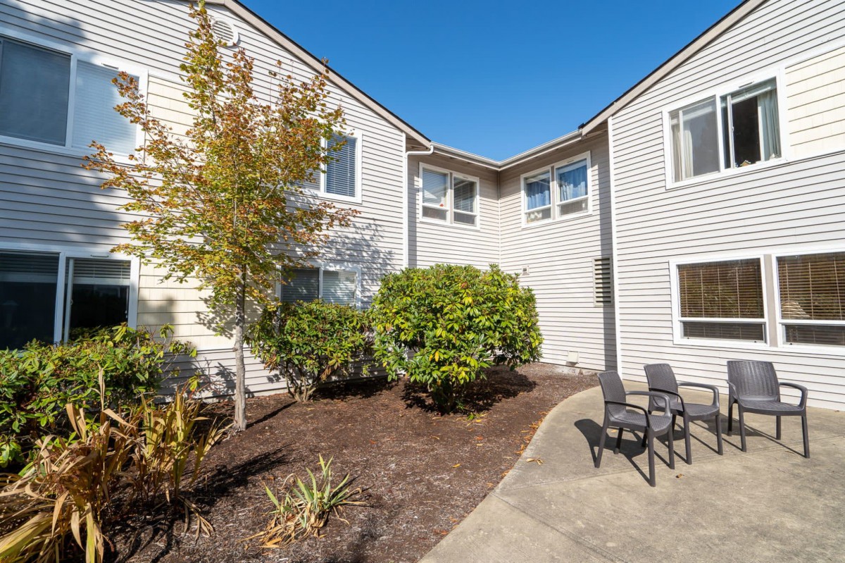 A well-maintained residential building with a small outdoor seating area on a sunny day.