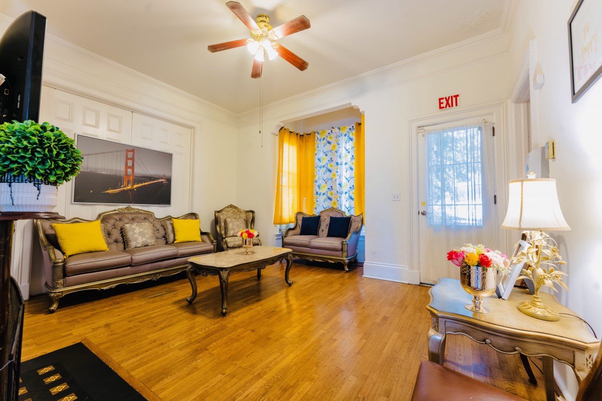 A cozy living room with stylish furniture, hardwood flooring, and a ceiling fan.
