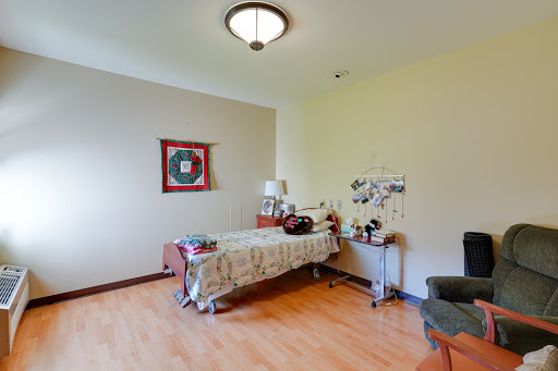 A cozy bedroom with a neatly made bed, decorative wall art, and warm wooden flooring.