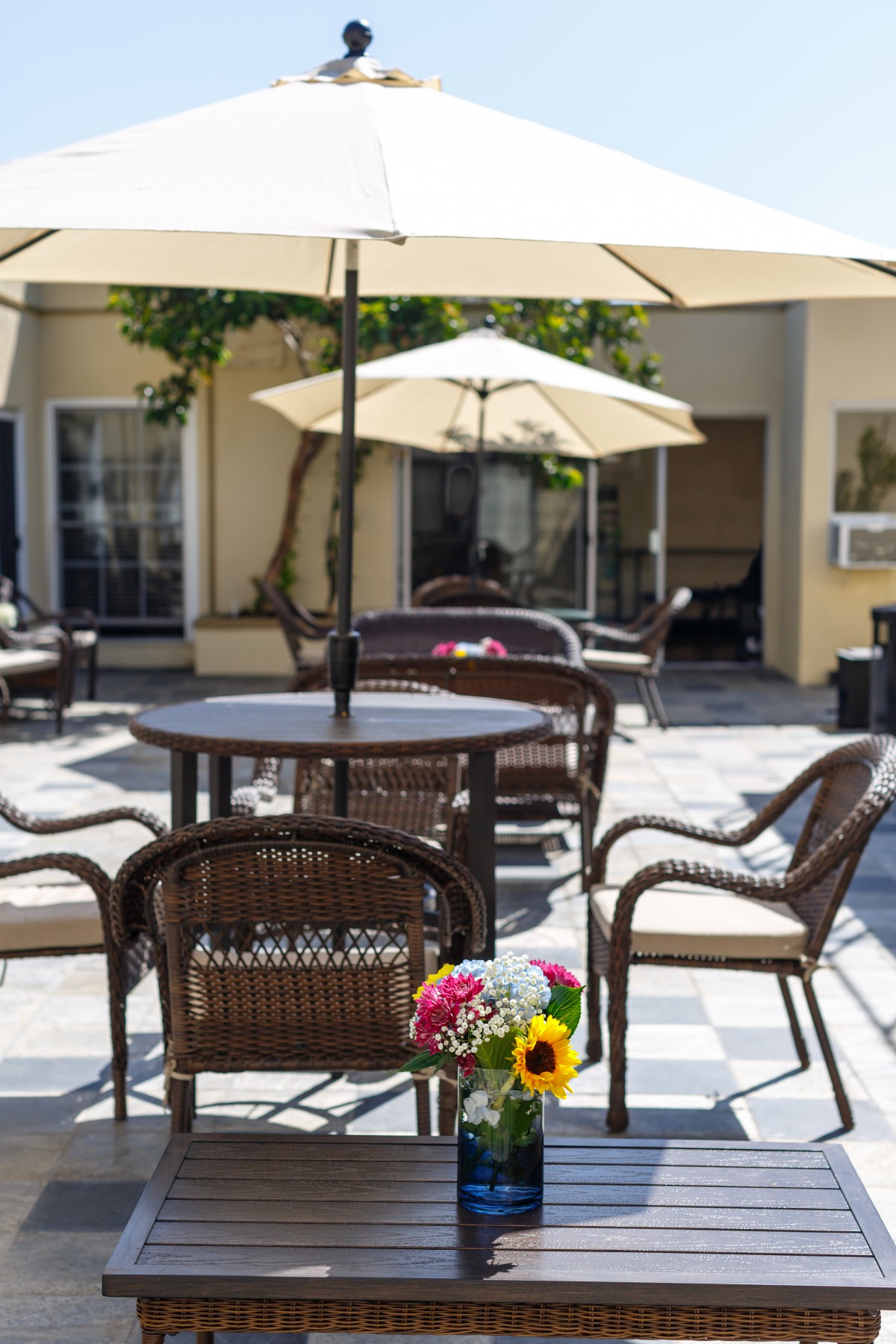 A cozy outdoor patio area with tables, chairs, and umbrellas, featuring a bouquet of flowers on the table.