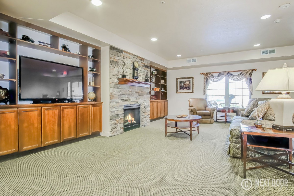 A cozy living room with a stone fireplace, television, and comfortable seating.