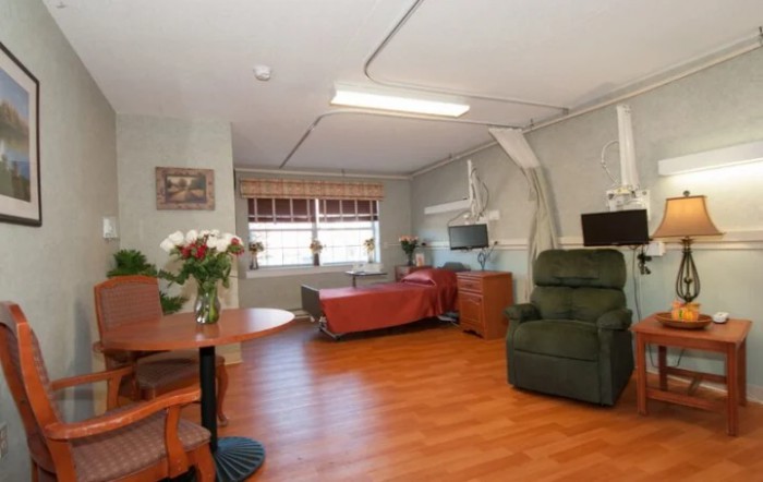 A clean and organized hospital room with a bed, chair, and medical equipment.
