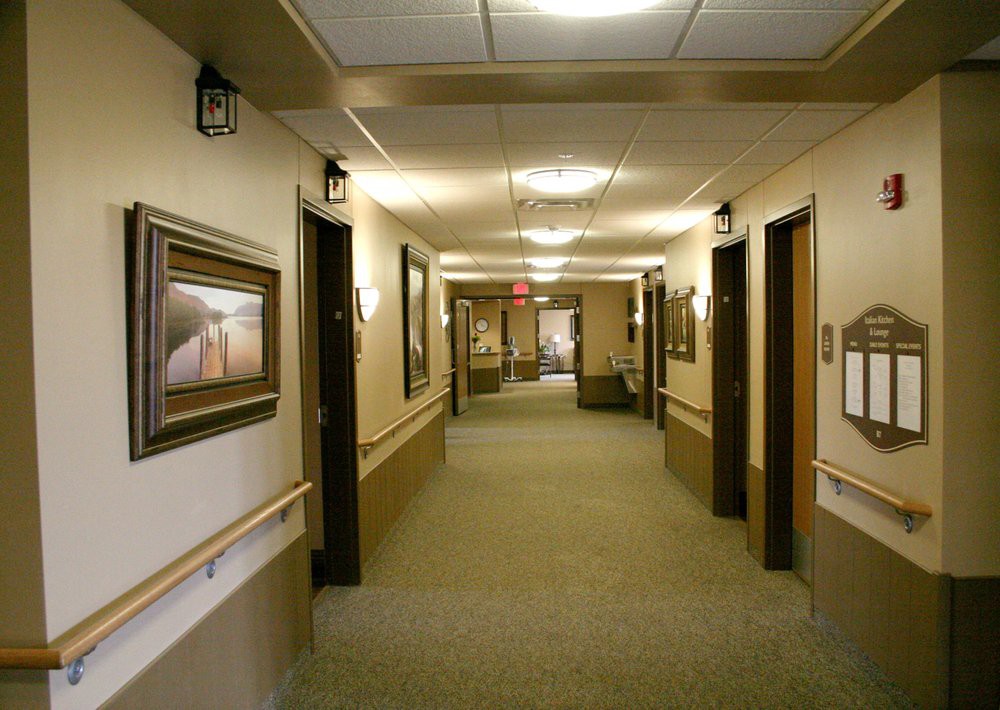 A well-lit corridor with framed artwork on the walls and multiple doors along its length.