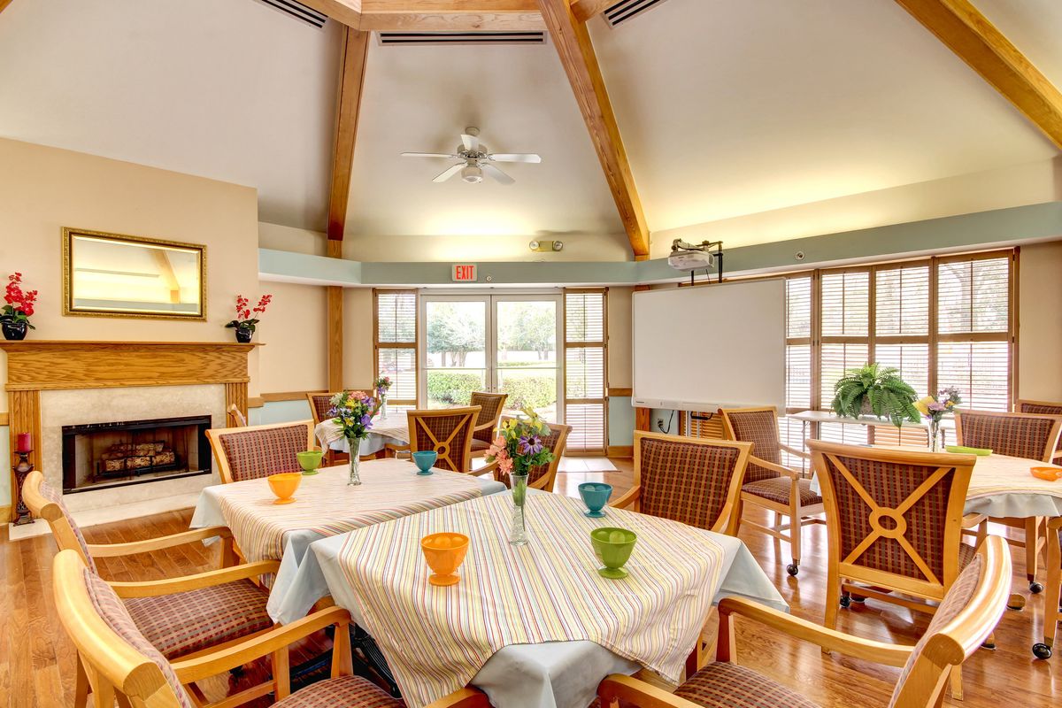 A cozy dining area with tables set for guests, featuring colorful cups and floral centerpieces.