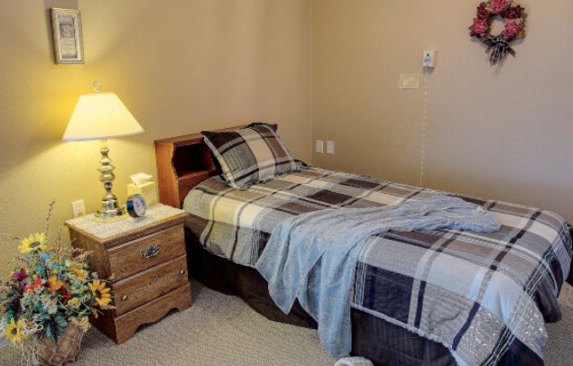 A cozy bedroom with a single bed, nightstand, and lamp.