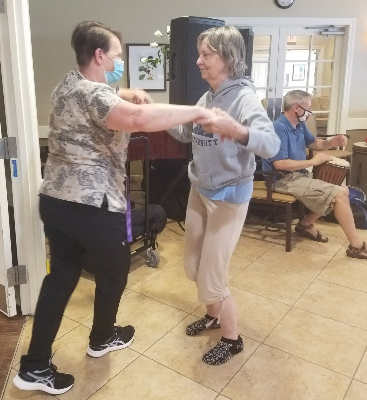 Two people dancing together indoors with a musician playing in the background.
