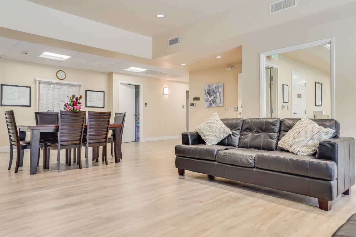 A modern living room with a leather sofa and dining area featuring wood flooring and contemporary decor.