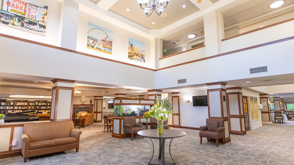A spacious and elegantly designed lobby featuring comfortable seating, decorative artwork, and a central table with flowers.
