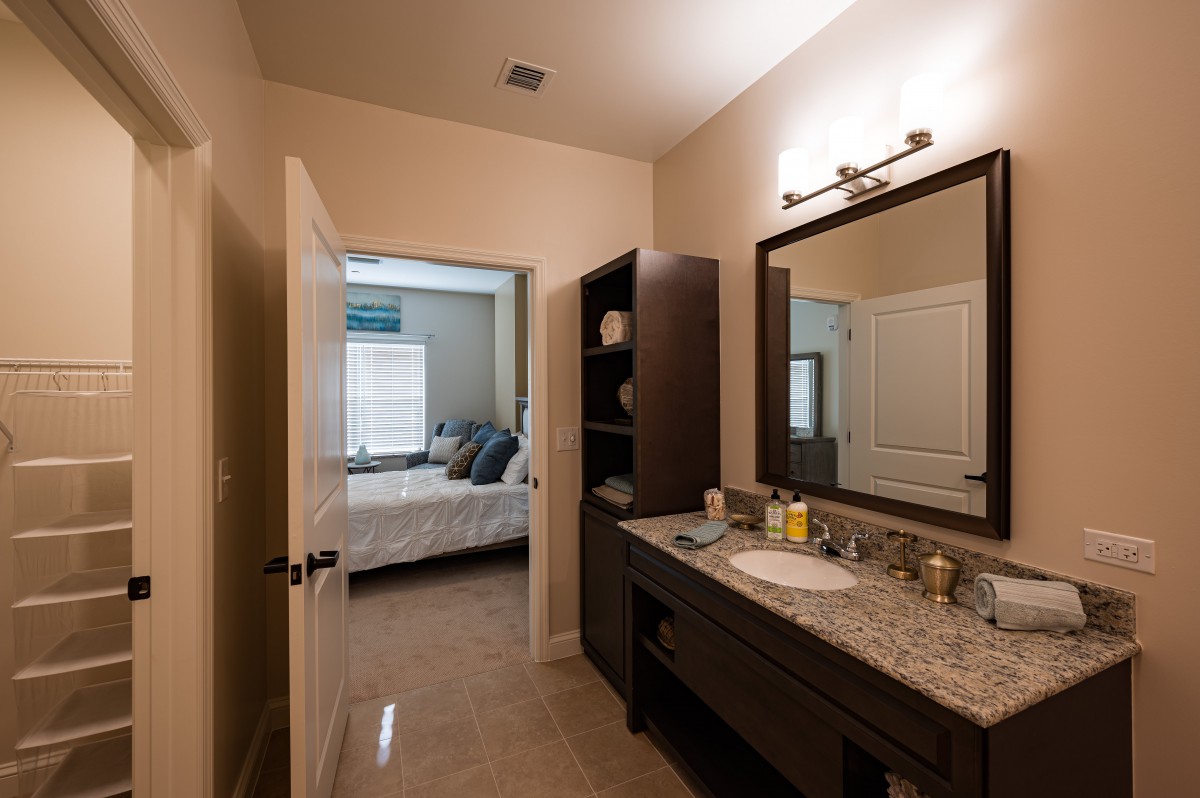 A view from the bathroom into the bedroom, featuring a sink and a mirror.