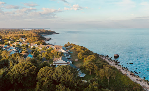 A serene coastal landscape showcasing a shoreline dotted with greenery and resort buildings, captured from an aerial perspective.