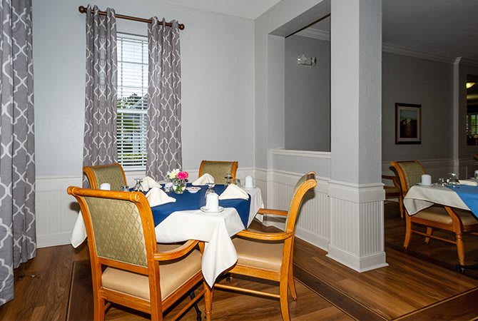 A cozy dining room with a neatly set table and cushioned chairs.