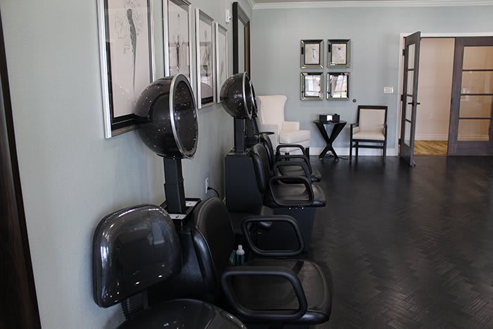 A salon interior with lined-up chairs and hair dryers.