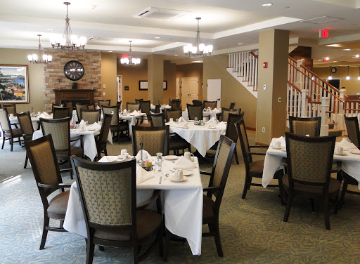 A neatly arranged dining room in a restaurant, featuring tables set with white linens and elegant chairs.