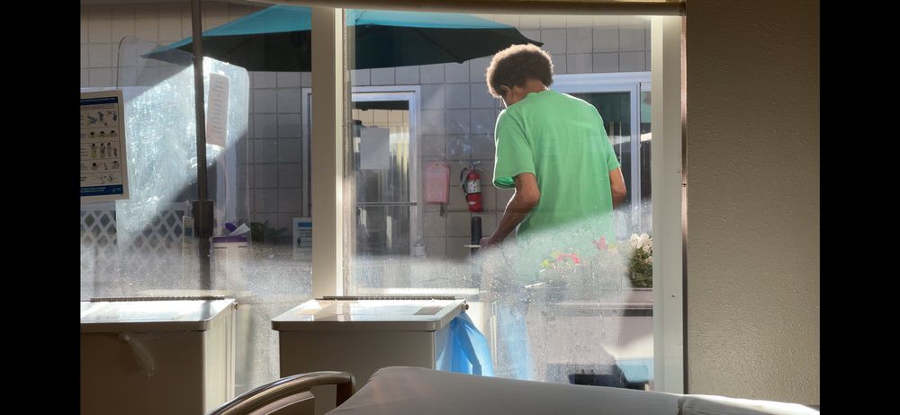 A person in a green shirt is visible through a window, with sunlight streaming in.