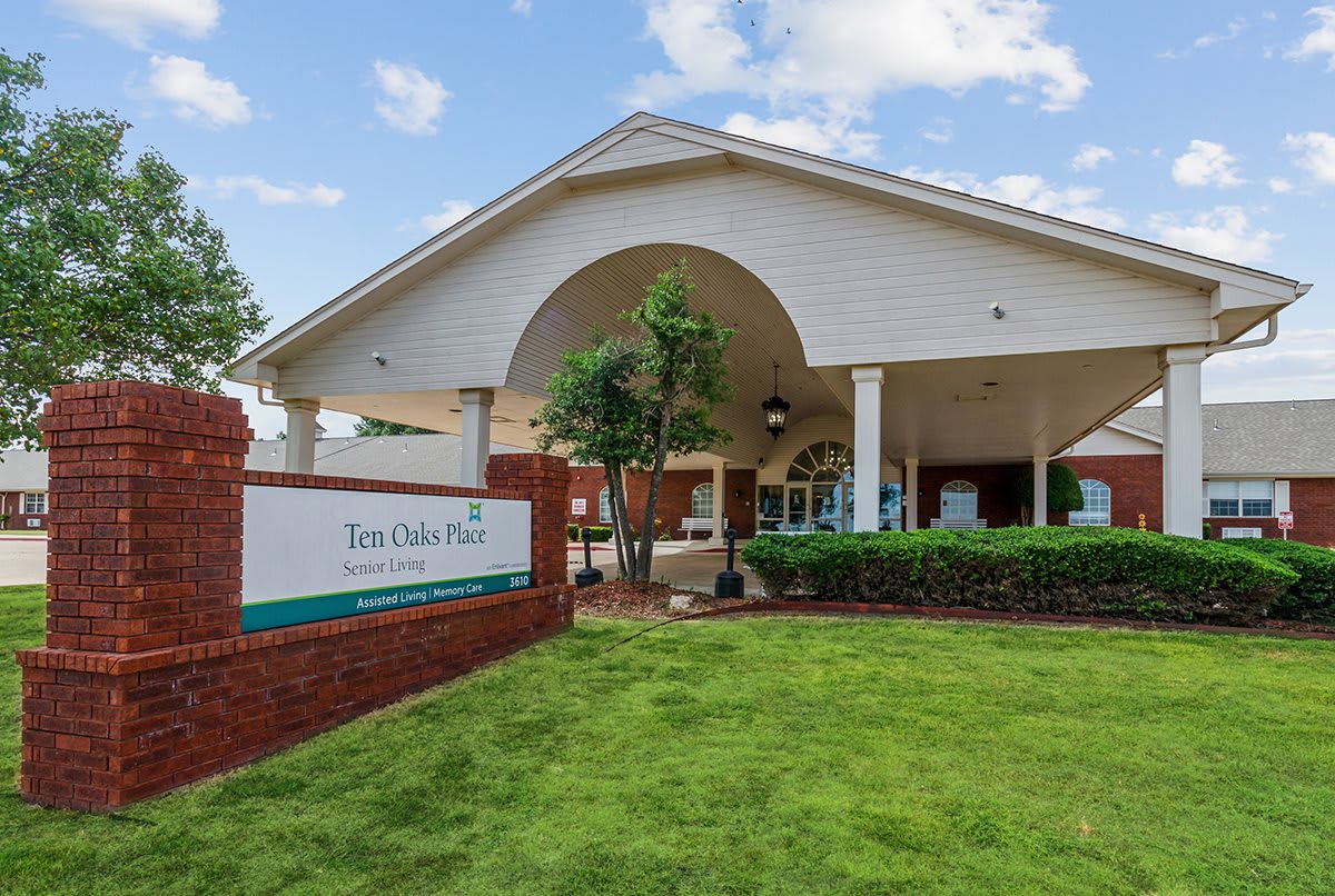Exterior view of a building with a brick sign and landscaped lawn.
