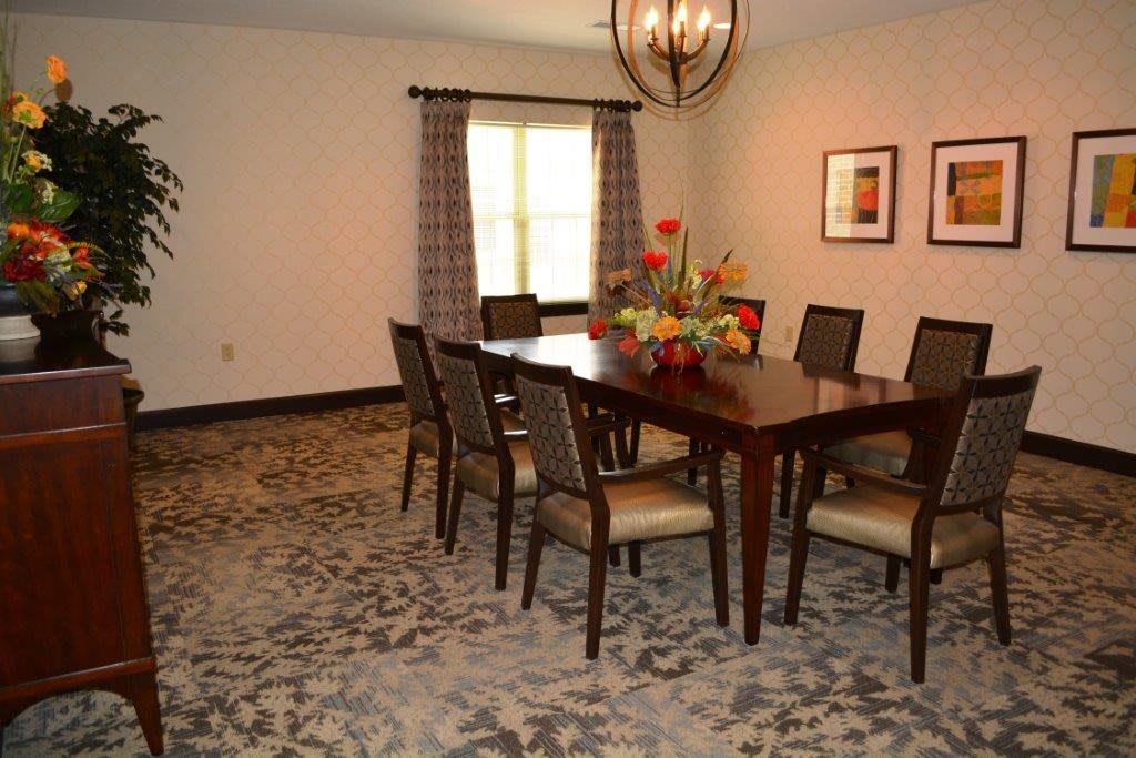 A cozy dining room with a large wooden table, matching chairs, and a decorative chandelier.