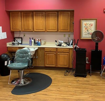 Interior of a barber shop with a styling chair, sink, and cabinets.