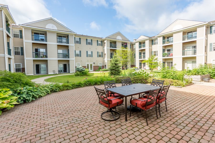 A well-maintained apartment complex with a central courtyard featuring outdoor seating and lush greenery.