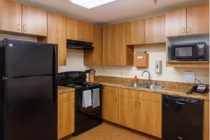 Modern kitchen with wooden cabinets and black appliances.