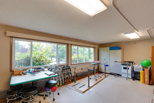A bright and spacious room with tables and chairs, featuring large windows that bring in natural light.