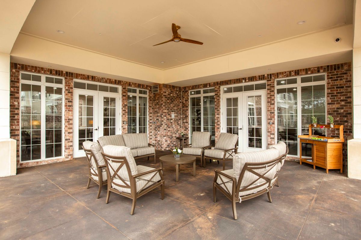 A cozy outdoor patio with seating and a ceiling fan.