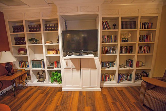 A cozy living room with built-in bookshelves surrounding a TV, set against a wooden floor.