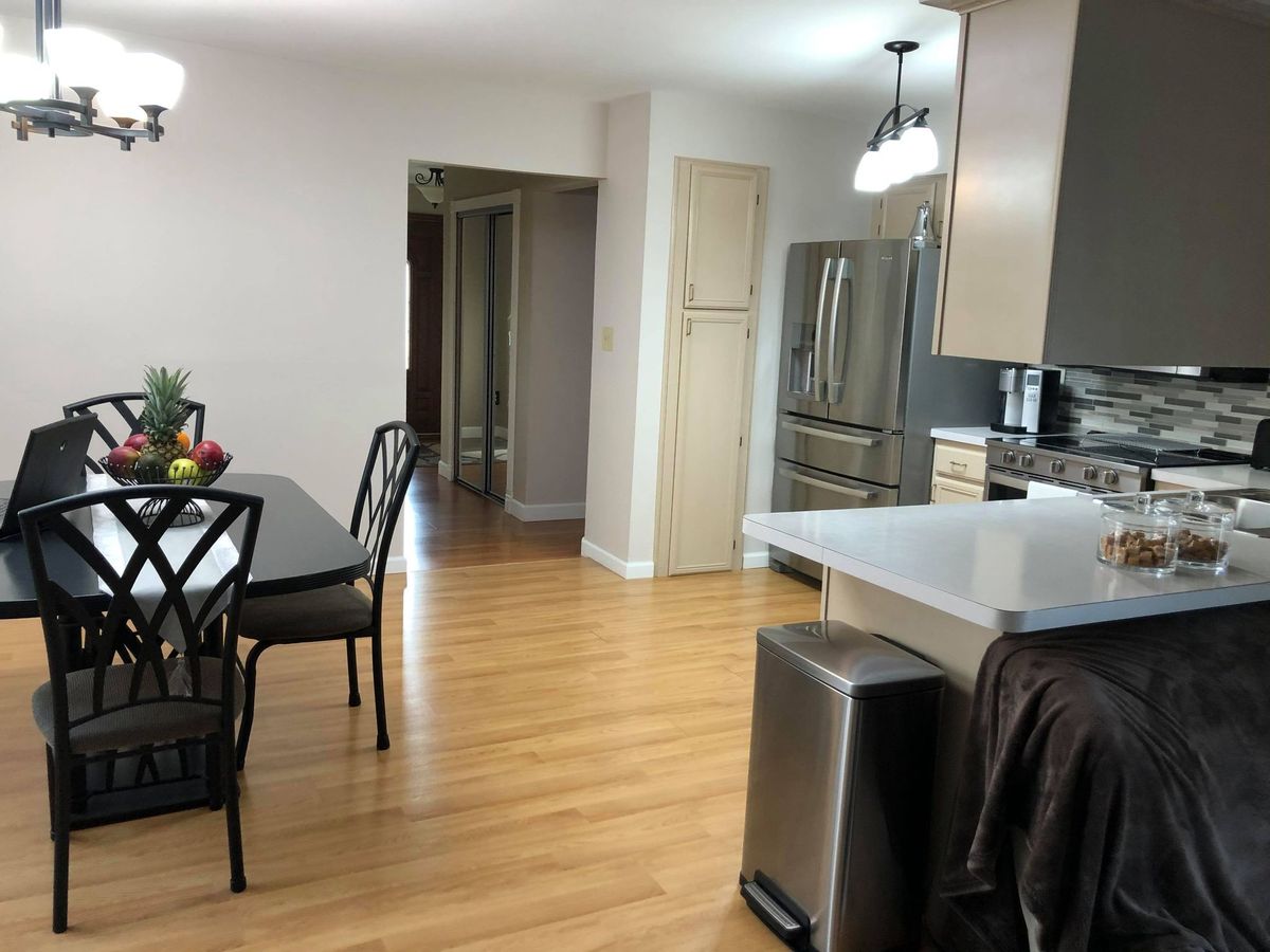 A modern kitchen and dining area with hardwood flooring and stainless steel appliances.